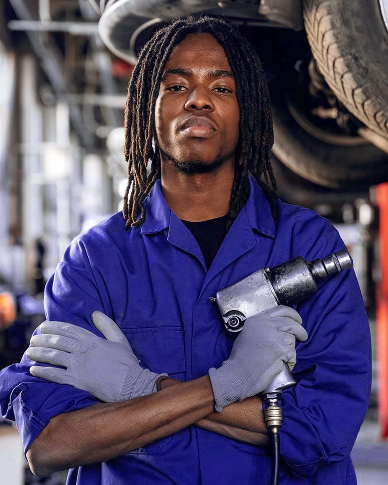 Kraftig mann med workwear og luftverktøy i bilverksted, klar for oppussing av biler i Bergen.